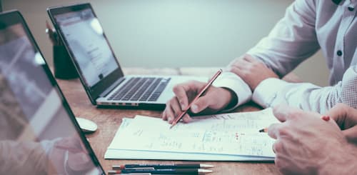 Wirtschaftlichkeit Zwei Männer arbeiten vor ihrem Laptops an Dokumenten
